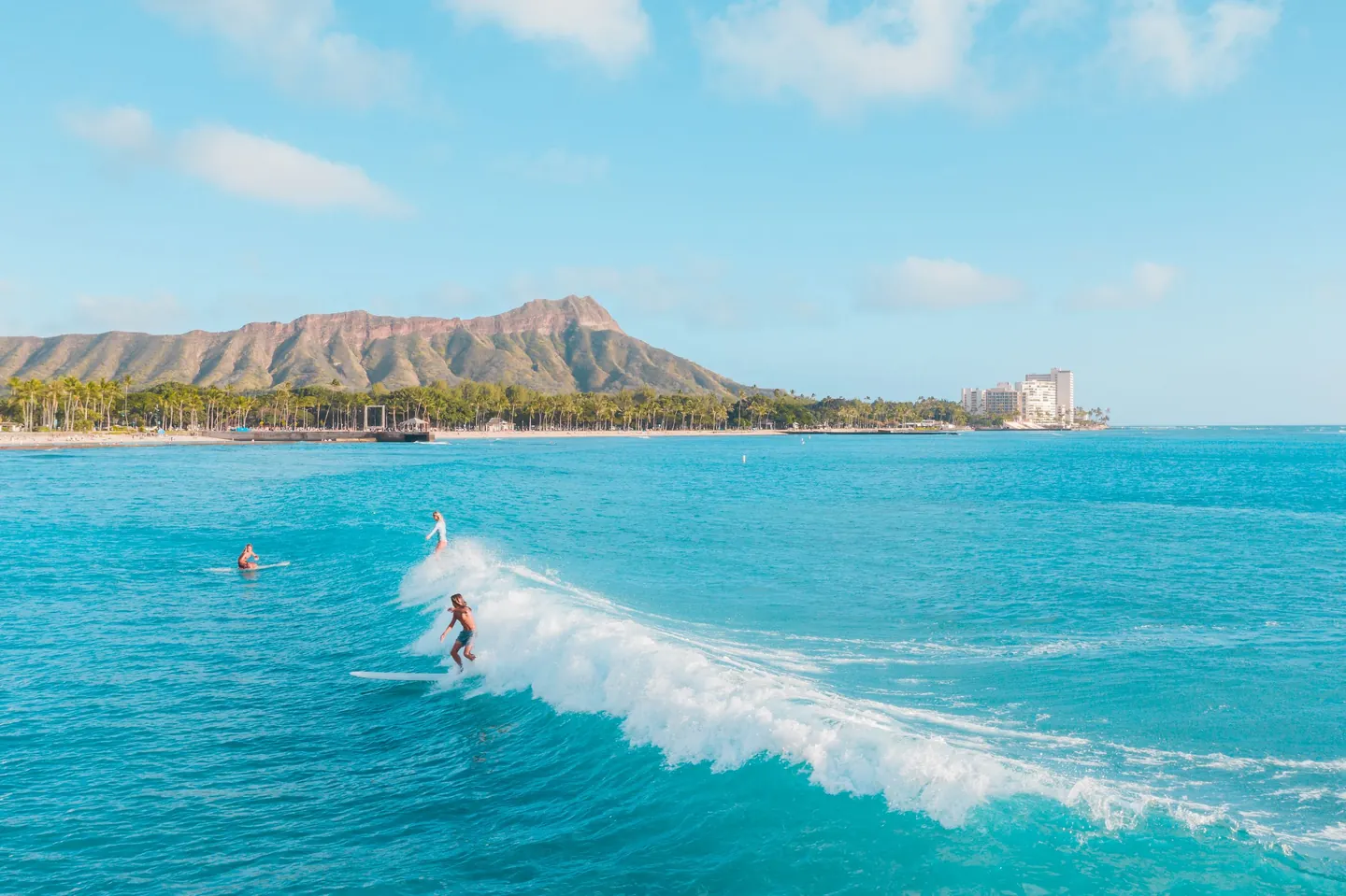 Surfers off Waikīkī with Diamond Head in the distance
